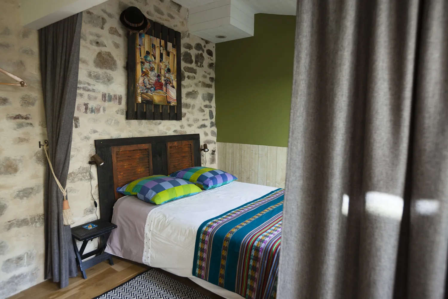 Vue de la chambre depuis l'entrée, rideau gris et literie colorée
