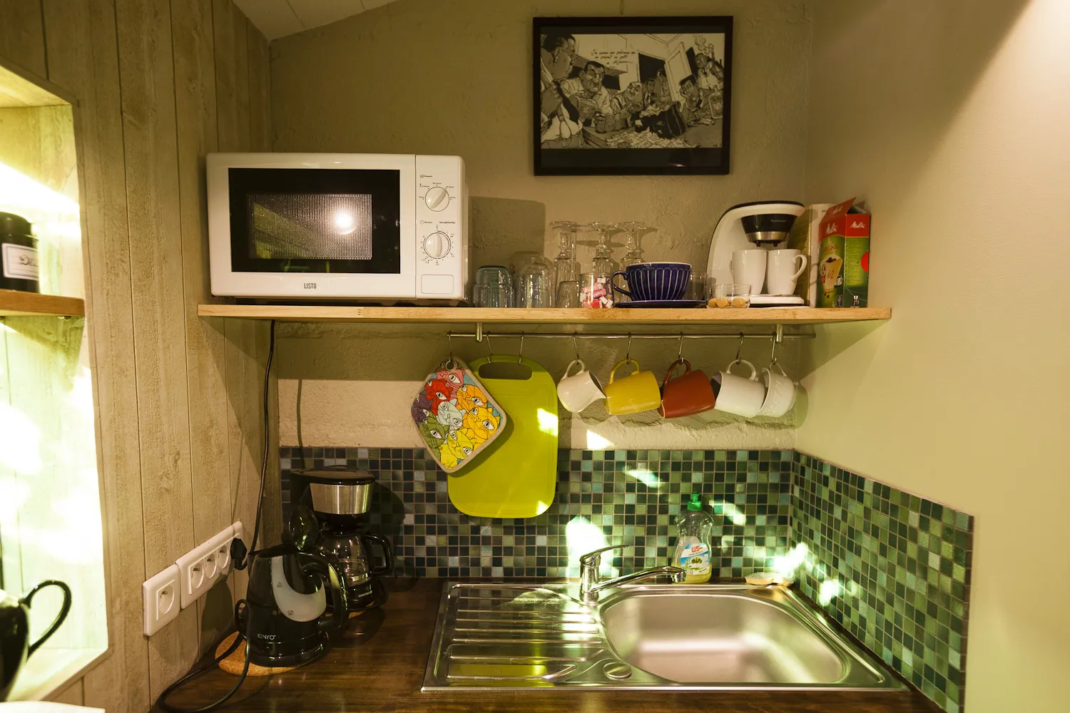 Kitchennette équipée avec micro-ondes, cafetière et carreaux mosaïque verts