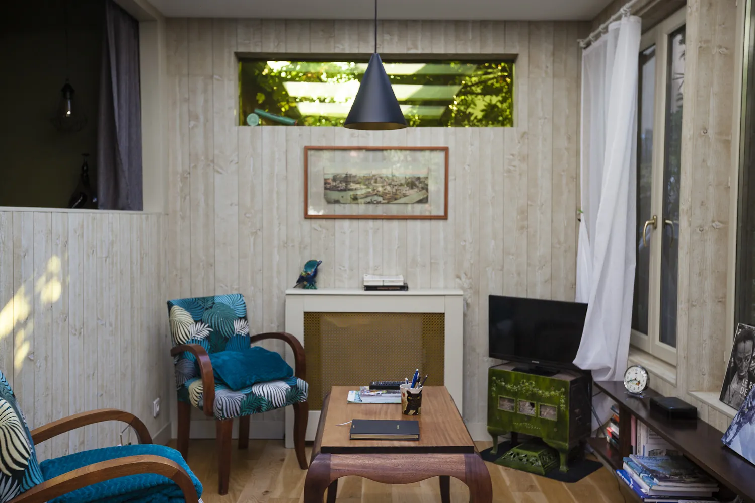 Détail du salon avec fauteuils tropicaux et poêle vert